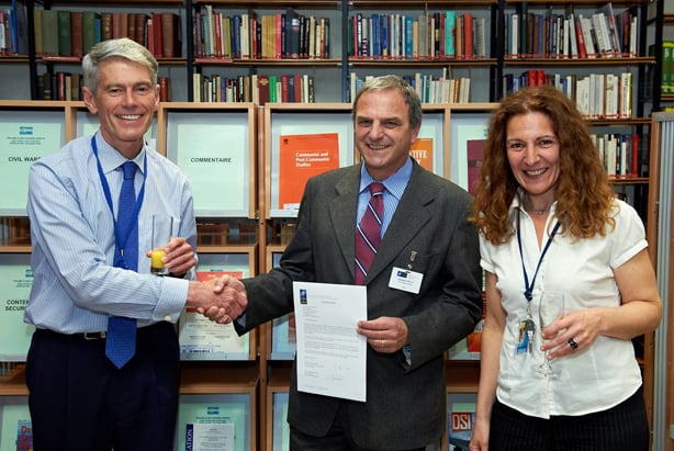 Mr Ted Whiteside, NATO Deputy Assistant Secretary General, shakes hands with Mr Giuseppe Vitiello, Head, NDC Library and Knowledge Centre. On the right, Mrs Isabel Fernandez, Head, NATO Multimedia Library