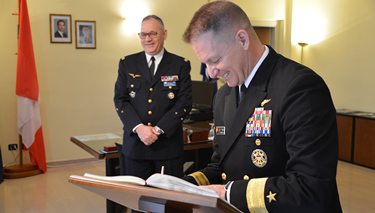 Rear Admiral Tynch signs the NDC guest book.